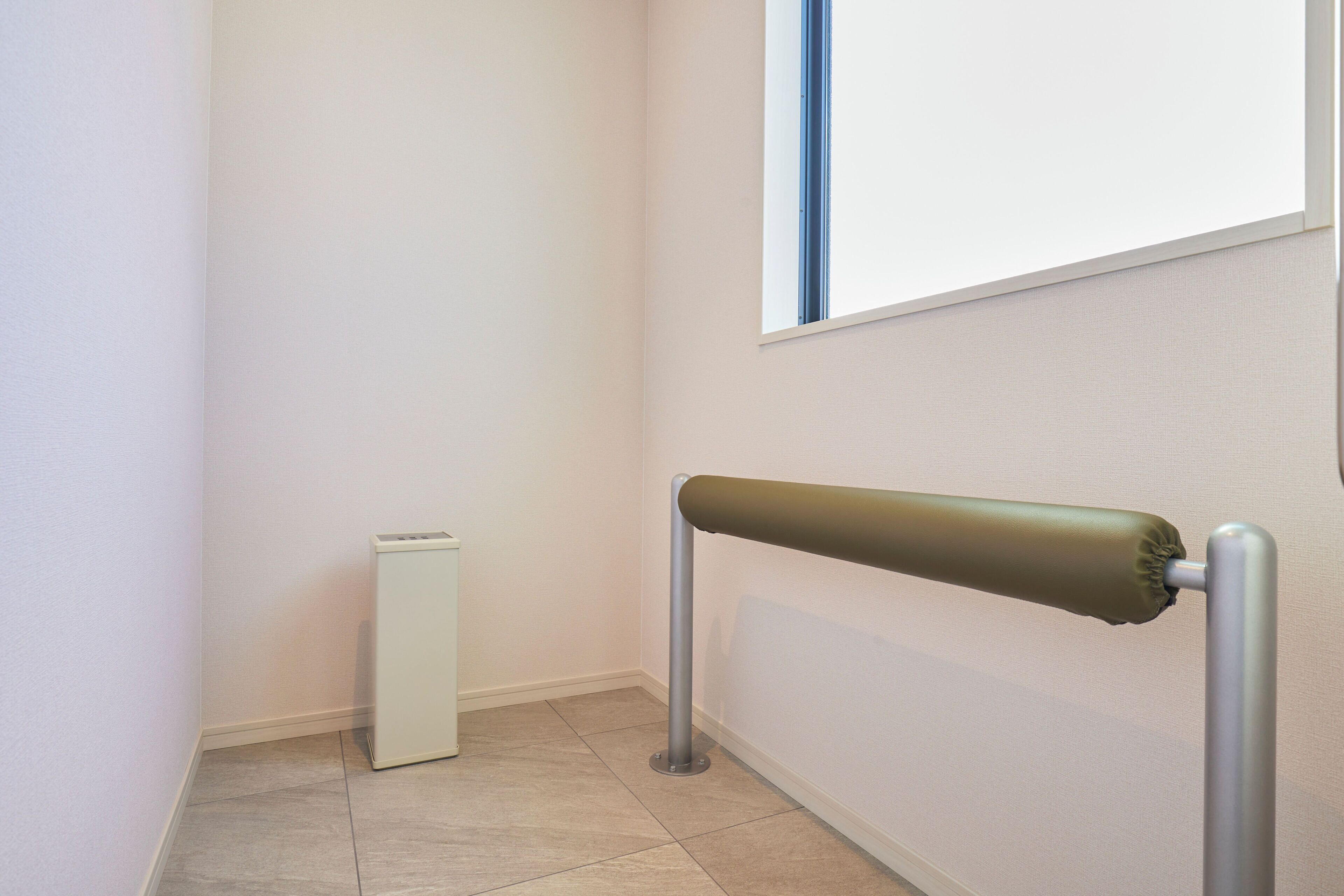 Un couloir étroit avec un radiateur, une main courante et une fenêtre.