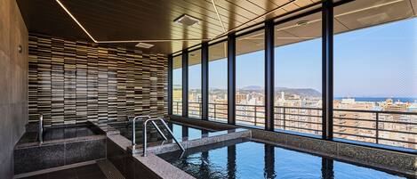 Una piscina infinita en el interior con vista a la ciudad, una pared de listones de madera y un diseño de techo moderno.