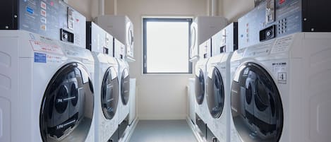 A laundry room with multiple washing machines, a window, and a door.
