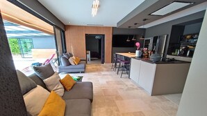 Un espacio moderno tipo sala con sofá, mesa de comedor y zona de cocina.