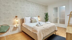 Une chambre à coucher avec un lit, des lampes de chevet, une plante et une lucarne.