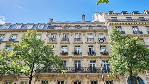 Un immeuble à plusieurs étages, doté de balcons décorés et de grandes fenêtres.