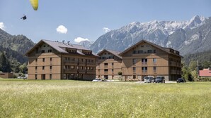 A multi-story building with balconies, a clear sky, and snow-capped mountains in the background.