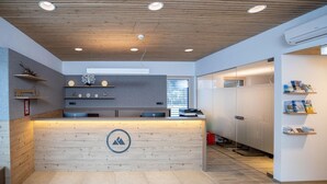 A modern reception desk with a wooden finish, a logo, and a glass partition.
