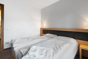 Une chambre d’hôtel avec deux lits, une tête de lit en bois, des lampes de chevet et une prise de courant visible.