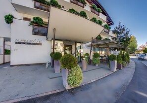 Un hôtel moderne doté d’une entrée abritée, de plantes en pot et offrant une vue sur un ciel dégagé.