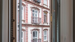 Une pièce avec une fenêtre donnant sur un immeuble doté de balcons.