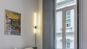 Une chambre d’hôtel avec un grand lit, un tableau au mur et une fenêtre avec des volets.