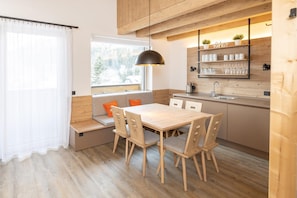 A modern kitchen with wooden cabinetry, a built-in bench seating, and a window with a view of trees. - Spacious 3-Bedroom Alpine Apartment for 7 Guests (Hinterstoder)
