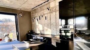 A modern kitchen with a large island, built-in appliances, and a stone wall. - Nettes Ferienhaus mit Privatem Pool by Interhome (Varna)