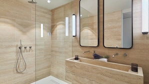 Een moderne badkamer met een douchecabine van glas, een grote spiegel en een marmeren wastafel.