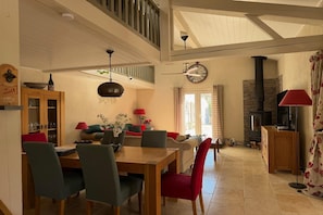 Amplia sala de estar con una mesa de comedor, sillas, un sofá, una chimenea y una escalera.