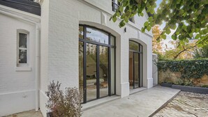 A modern white brick building with large arched windows and a concrete patio. - Architect house Porte Maillot  la Defense Arena (Puteaux)