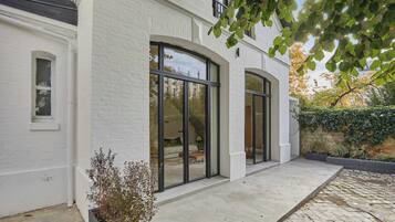 A modern white brick building with large arched windows and a concrete patio.