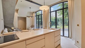 A modern kitchen with a large island, a sink, and a dining area with chairs and a table. - Architect house Porte Maillot  la Defense Arena (Puteaux)