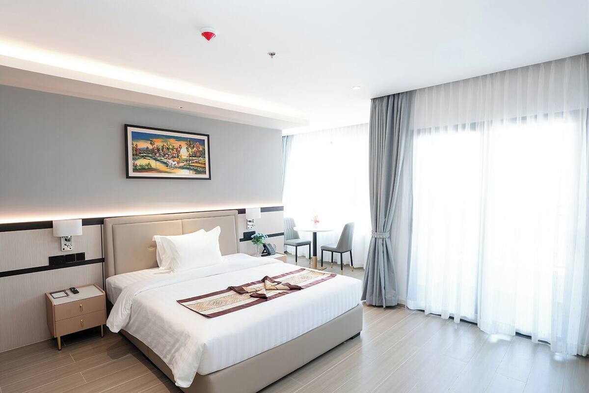 Una habitación de hotel moderna con una cama grande, mesitas de noche, un escritorio y una silla.