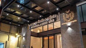The exterior of a hotel with a modern design, featuring a prominent entrance with glass doors and a sign displaying the hotel name in multiple languages. - LN Hotel & Residence  (Phnom Penh)
