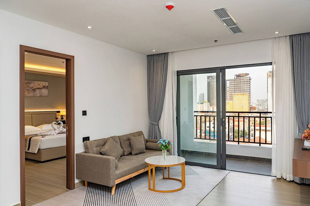 Una habitación de hotel moderna con un sofá, una mesita y vistas a la ciudad a través de amplios ventanales.