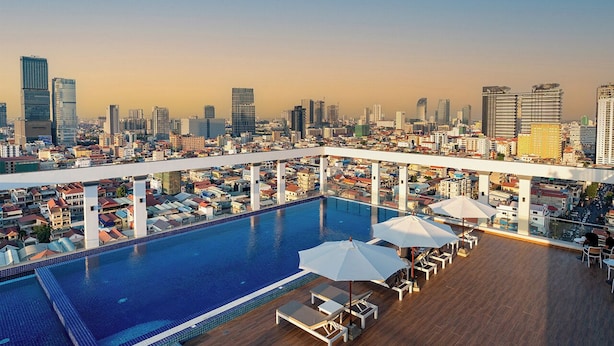 A rooftop pool with a city view, lounge chairs, and umbrellas. - LN Hotel & Residence  (Phnom Penh)