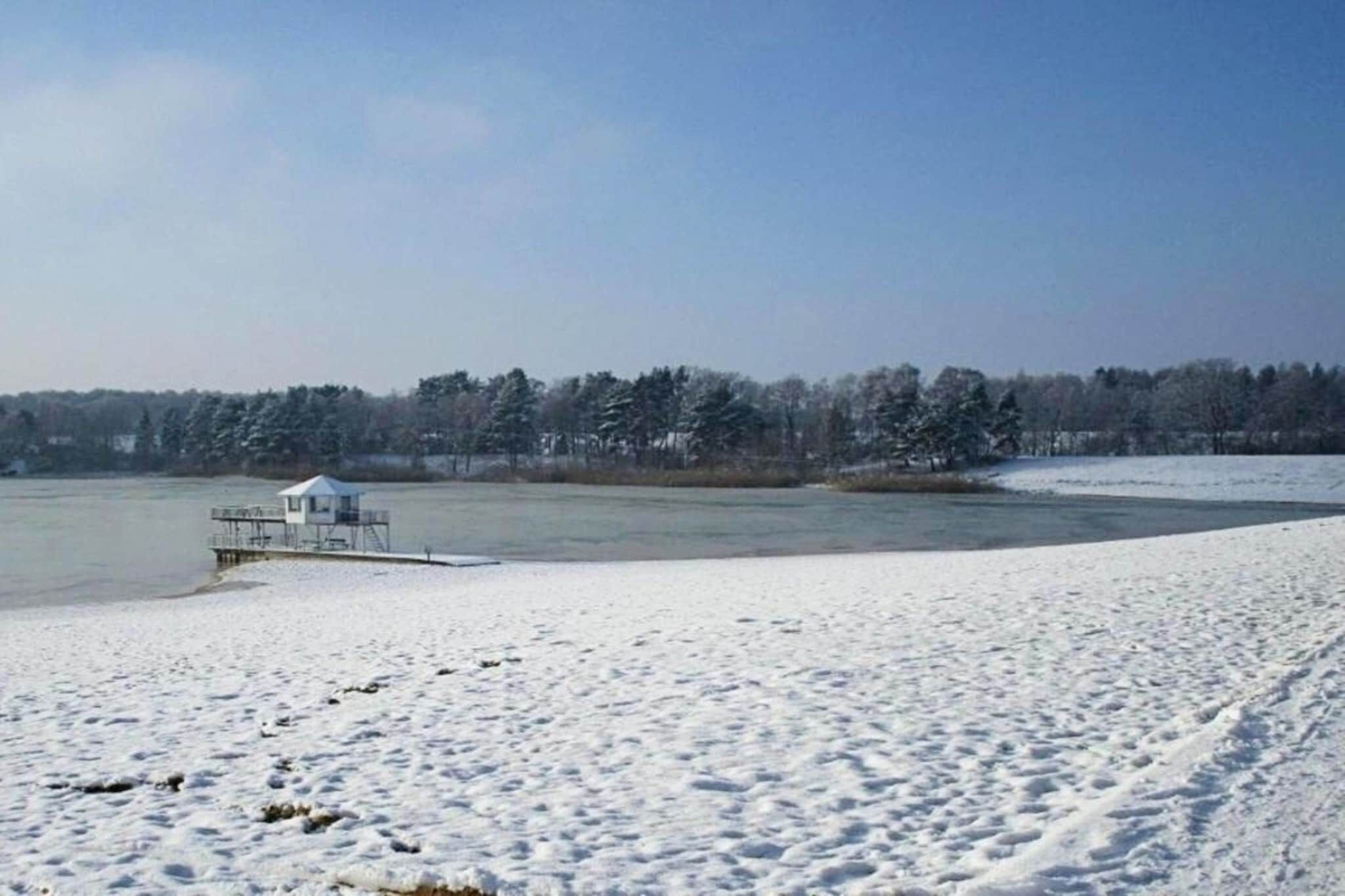 A snow-covered beach with a lifeguard tower and a clear view of the water.