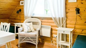 A cozy room with a sloped ceiling, a wicker chair, a white table, a small white cabinet, and a window with sheer curtains. - mit eigenem Parkplatz by Interhome (Ulbroka)