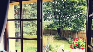 A room with a large window overlooking a wooden deck with outdoor furniture and a garden. - mit eigenem Parkplatz by Interhome (Ulbroka)