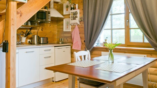 A cozy kitchen with wooden beams, a microwave, a stove, and a window with curtains. - mit eigenem Parkplatz by Interhome (Ulbroka)