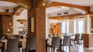 Ein Restaurant mit Ziegelwänden, Holzbalken und mehreren Tischen mit Stühlen.