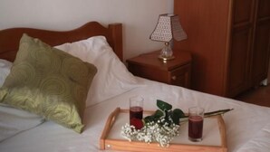 A neatly made bed with a tray of drinks and flowers, a lamp on a bedside table, and a wooden wardrobe in the background. - Wohnung mit Pool by Interhome (Bar)