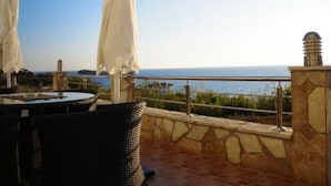 A terrace with a view of the sea, featuring outdoor seating and umbrellas. - Wohnung mit Pool by Interhome (Bar)