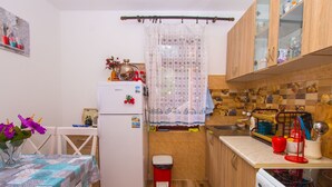 A compact kitchen with wooden cabinets, a refrigerator, a sink, and a stove. - Familienfreundliche Wohnung direkt am Meer by Interhome (Dobrota)
