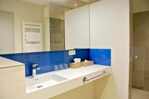 Un baño moderno con un lavamanos blanco, salpicadero de azulejos azules y cabina de ducha de vidrio.