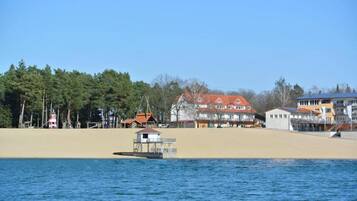 Ett kustområde med en sandstrand, en liten båt och byggnader med röda tak.
