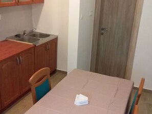 Een compacte keuken met een spoelbak, houten kastjes en een tafel met een witte tafelkleed.