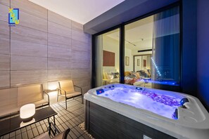 Ein modernes Badezimmer mit Whirlpool, einer Sitzecke und Blick auf die Stadt durch große Fenster.