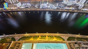 Een nachtzicht van een hotel aan het water, met een groot verlicht zwembad en een bord waarop 'BINGHATTI' staat.