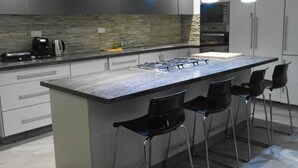 Een moderne keuken met een centraal eiland, barstoelen en hanglampen.
