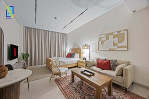 Ein modernes Hotelzimmer mit Bett, Sofa, Couchtisch, Fernseher und einem großen abstrakten Gemälde an der Wand.