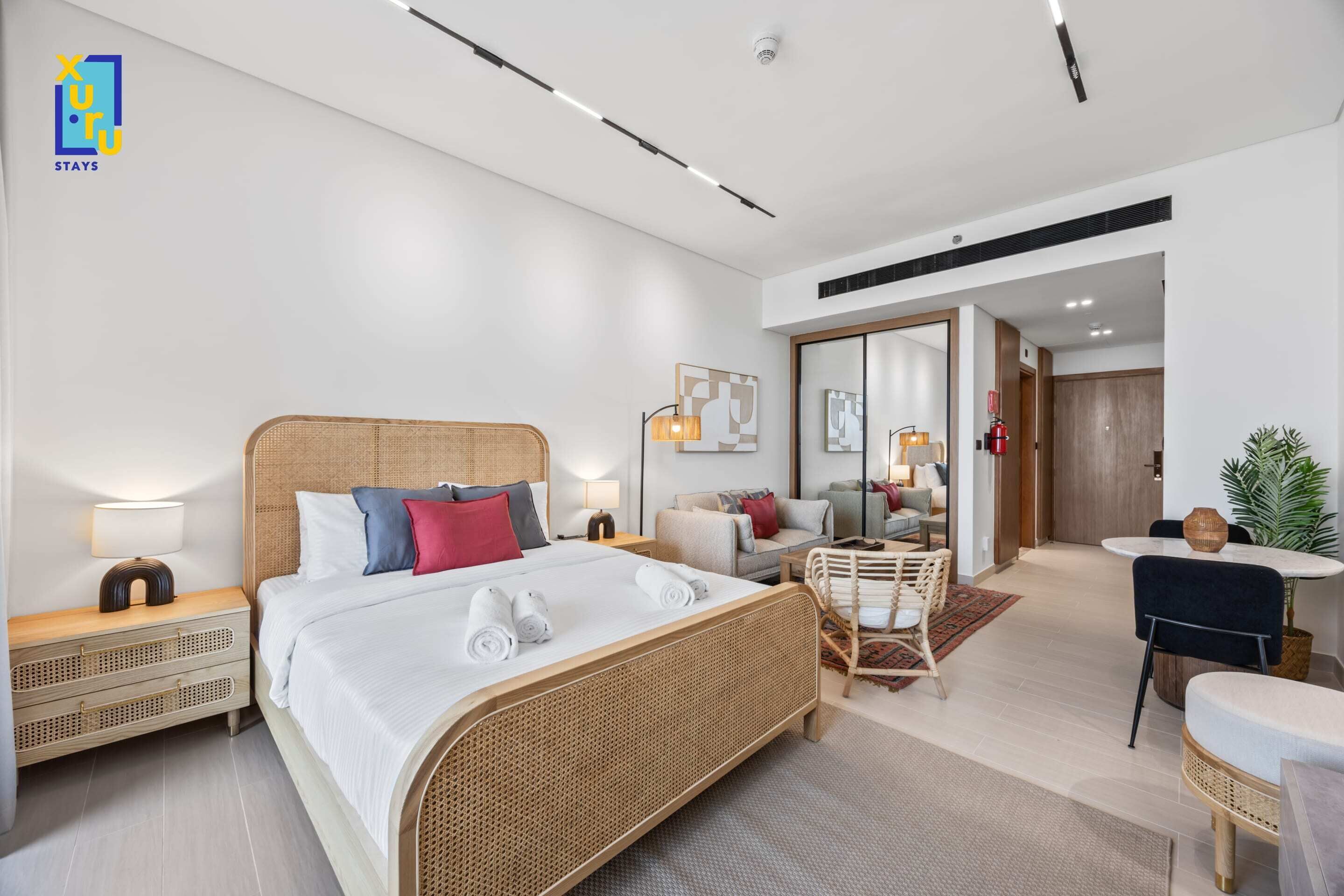 Una camera d'albergo moderna con un letto grande, comodini, una zona relax con un tavolino e uno specchio.