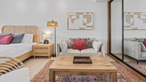 Quarto moderno com cama, mesa de cabeceira, luminária e um sofá.