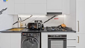 Uma cozinha compacta equipada com máquina de lavar, micro-ondas, fogão a gás e forno embutido.