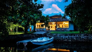 Una casa con porche cubierto y un barco amarrado al agua.