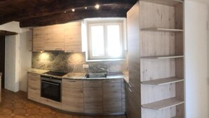 Een moderne keuken met houten kastjes, een inbouwoven en een raam dat voor natuurlijk licht zorgt.