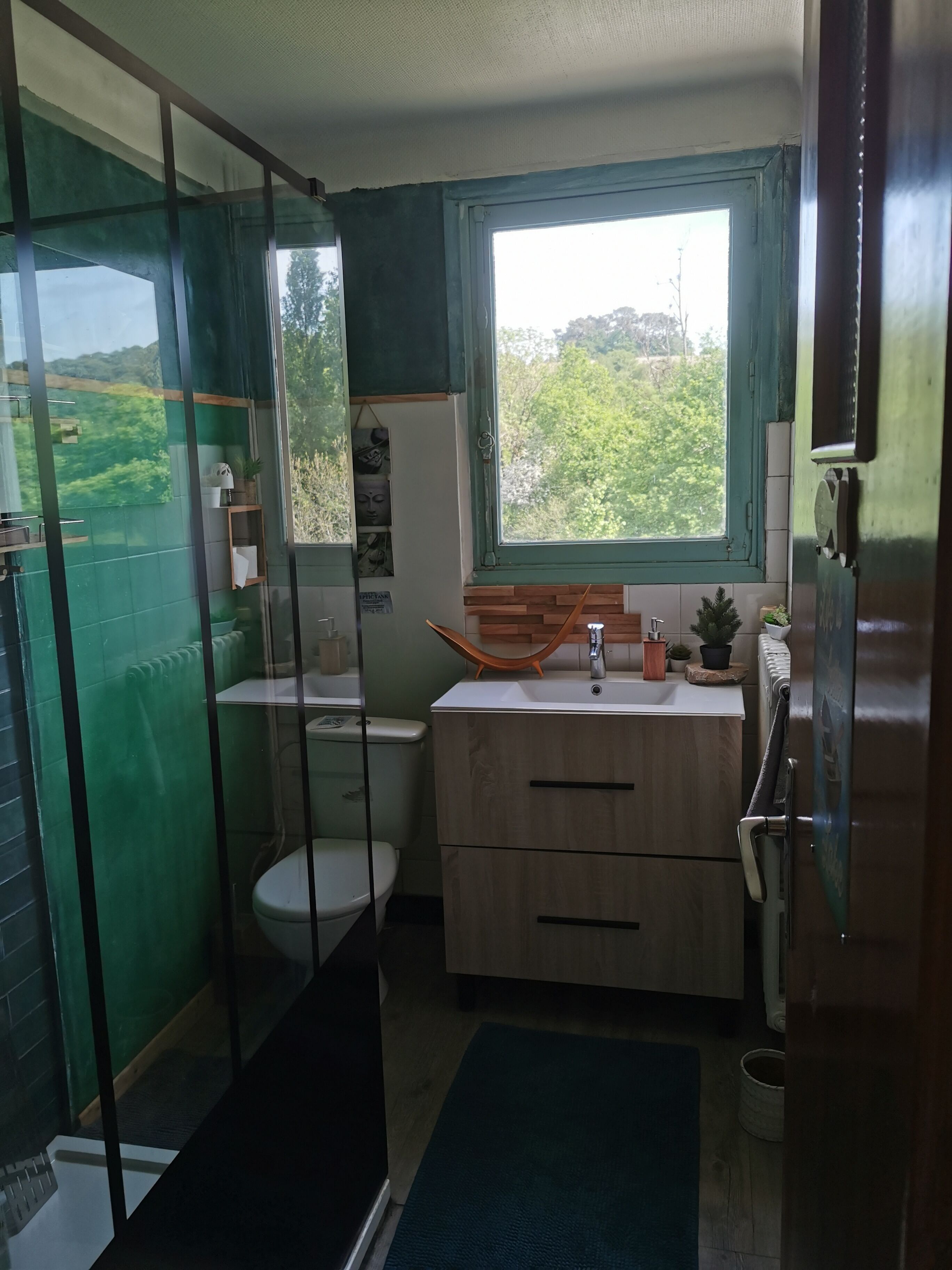Un baño con inodoro, lavamanos, espejo, ventana y zona de ducha.