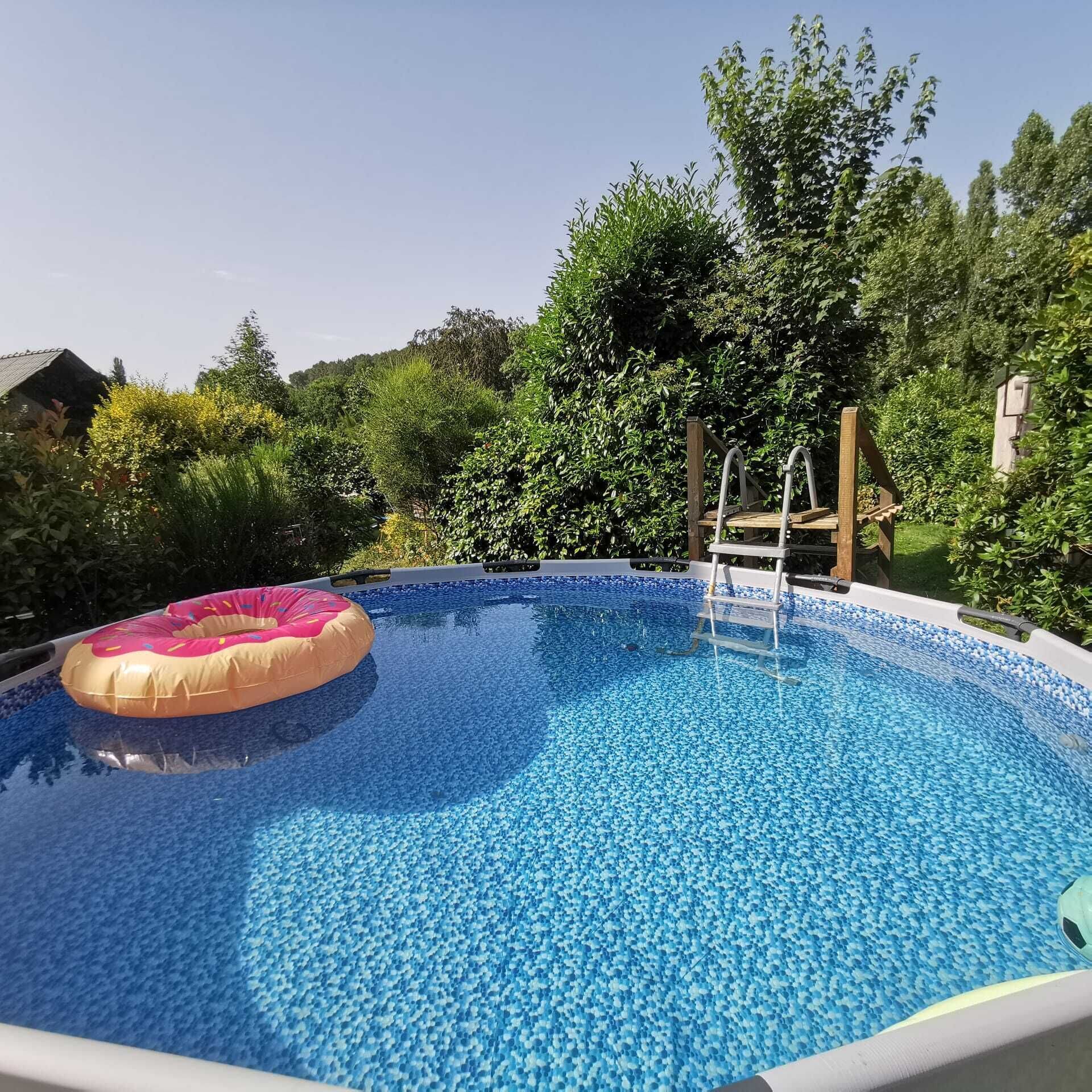 Une piscine avec un escalier, entourée d’une végétation luxuriante.