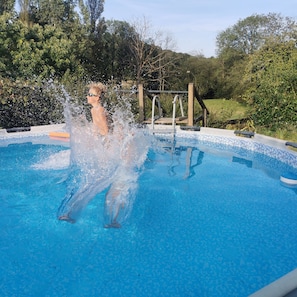Una piscina con agua azul cristalina, rodeada de vegetación y una terraza de madera.