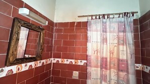 A bathroom with red tiled walls, a wooden-framed mirror, and a zebra-patterned shower curtain.