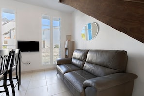 Una sala de estar con sofá, televisor y comedor.
