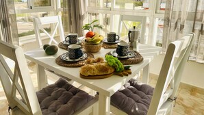 Un tavolo da pranzo con una macchina per il caffè, tazze, frutta e pane.