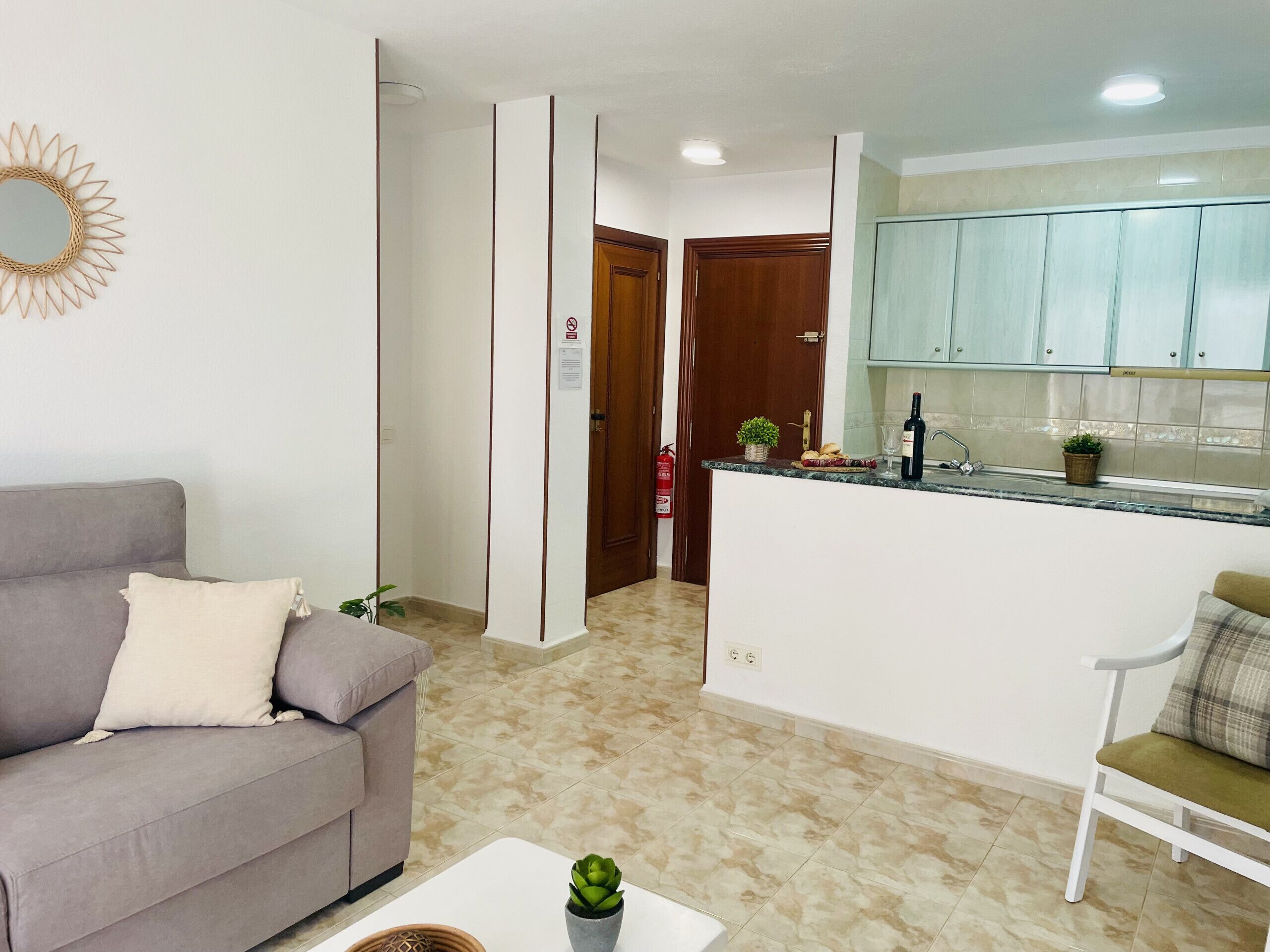 Ein Wohnzimmer mit Sofa, Couchtisch und Küchenzeile inklusive Schränke und Arbeitsplatte.